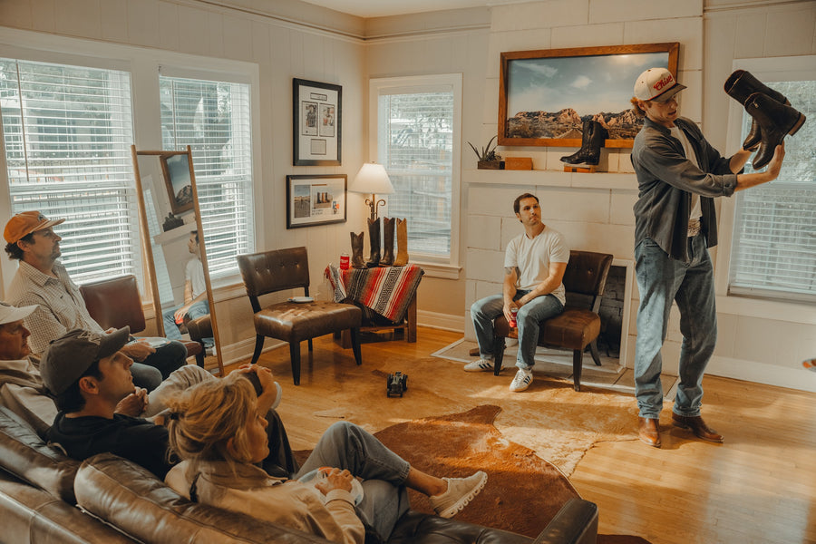 A cowboy boot is held up for a seated group during a boot fitting at Chisos HQ