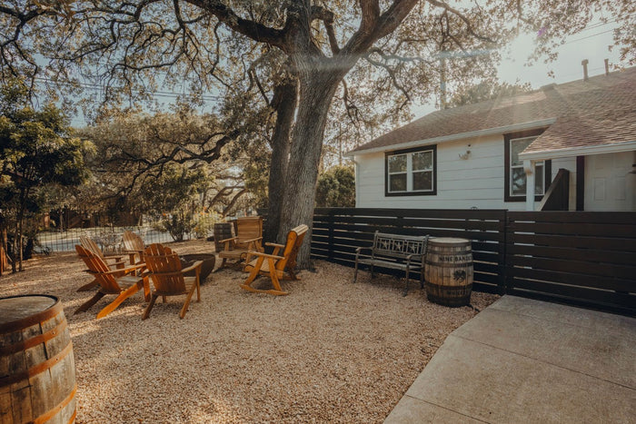 Wooden chairs and barrels under a big shade tree in the Chisos HQ backyard