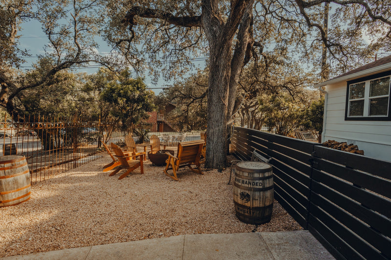 The fenced backyard at Chisos HQ with chairs and barrels