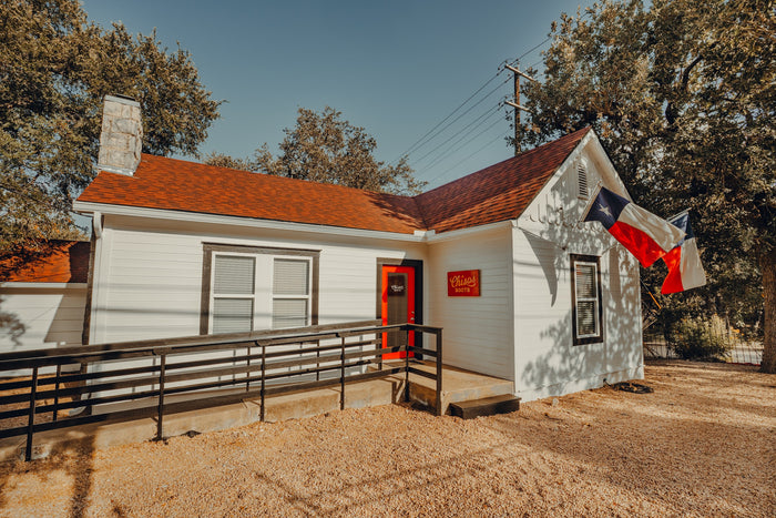 Chisos HQ on South 1st Street in Austin, a white house with a red roof and a Texas flag
