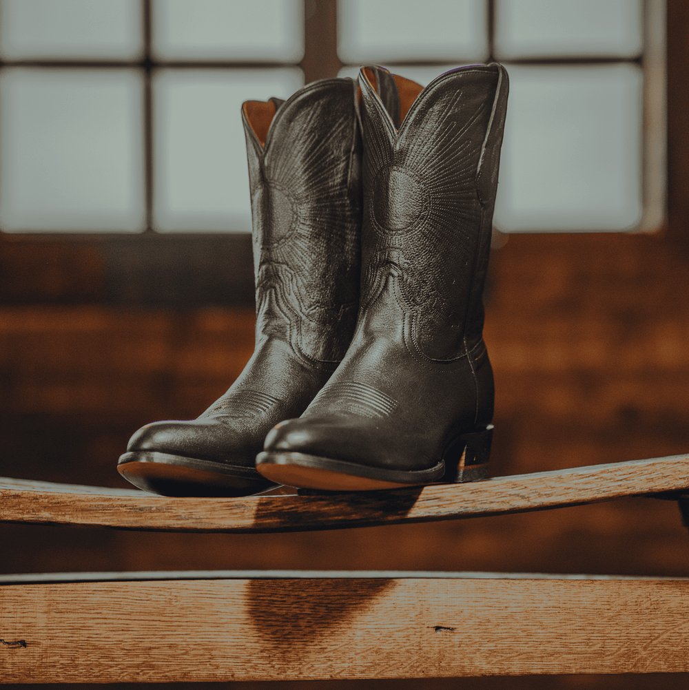 Chisos No. 1 black cowhide round toe wedding cowboy boots displayed on bench